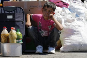 Syrian boy sits beside his family's belongings at border gate in Turkey