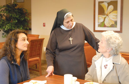 Sr. Mary Giovanni Monge, CSSF, director and CEO of Angela Hospice, chats with a resident and family member during the weekly Thursday “high tea.”