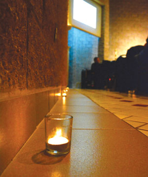 Candes burn along the walls of the St. Mary of the Hills Chapel as music director Daniel Grieg leads the congregation in song. 