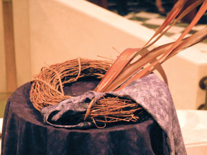 The baptismal font is adorned with a crown of thorns, reeds and a purple cloak: symbols of Christ’s passion.