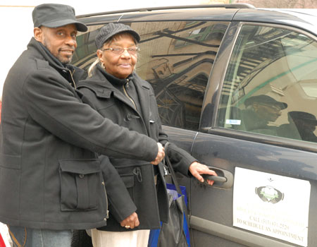 Senior advocate driver Ron Walker helps Linda Farley into a St. Pat’s transportation vehicle. Farley, who no longer drives, calls this resource “a blessing.” For Walker, a senior himself, this is a way of “giving back” to the community.
