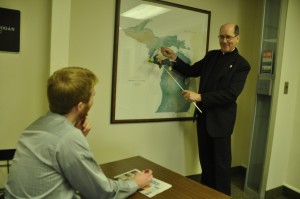 Msgr. Ronald Browne, a Detroit priest who formerly worked as moderator of the curia for the Diocese of Marquette, shows Michigan Catholic managing editor Mike Stechschulte a map of the state of Michigan for the first time. Stechschulte, incredulous, replied, “Has that been there the whole time?”