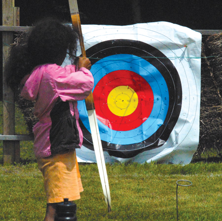 A young camper lines up her perfect shot while participating in archery at Camp Ozanam. 