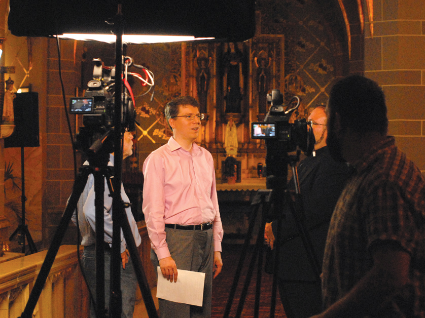 Alex Begin, executive producer and host of the new TV series “Extraordinary Faith,” plans a scene with his film crew June 25 at St. Florian Parish in Hamtramck. Begin is a native Detroiter.
