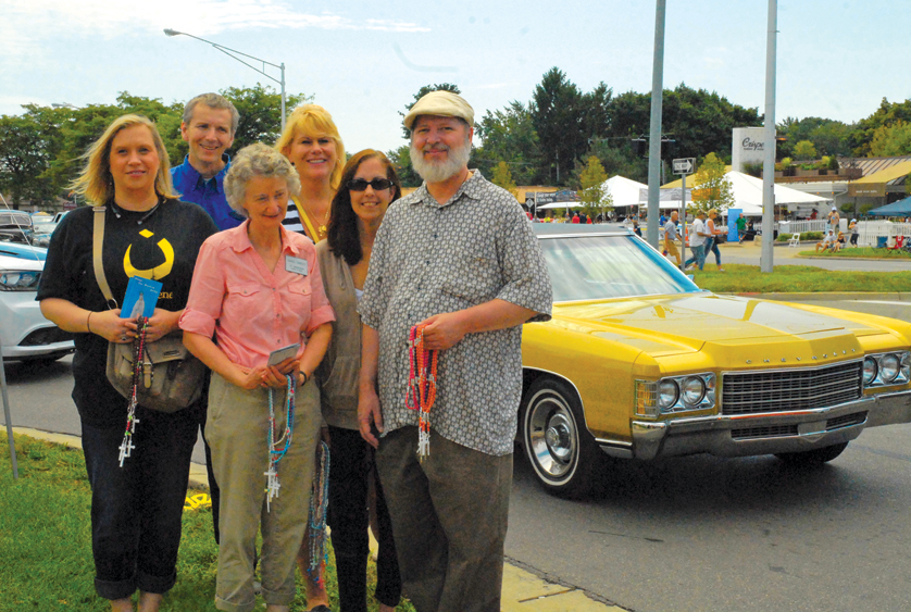 Members of the Legion of Mary in Michigan, (clockwise) Wendy Anderson (Nazarene shirt), Bruce Higgins, Lisa Ashman, GayAnne Chaney, Scott Chaney and Carol Tardiff hand out rosaries and religious books to passersby during the annual Woodward Dream Cruise outside National Shrine of the Little Flower Parish in Royal Oak.