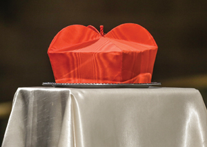 Cardinal Szoka’s biretta is placed on a table, alongside his cosier, next to the casket. 