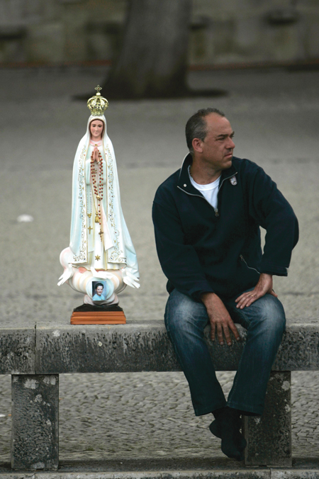 A pilgrim sits next to a statue of  Our Lady of Fatima at the Marian shrine of Fatima in central Portugal May 11. Pope Benedict XVI began a four-day Portuguese visit that was to include the shrine. (CNS photo/Rafael Marchante, Reuters) (May 10, 2010)See PORTUGAL-ARRIVAL May 11, 2010. 