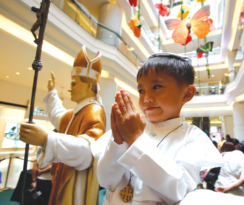 A boy prays next to a statue of St. John Paul II at an exhibit of the pontiff's relics in Manila, Philippines, April 27. That day Pope Francis canonized Sts. John Paul and John XXIII at the Vatican. (CNS photo/Erik De Castro, Reuters) (April 27, 2014)