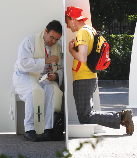 A priest hears confession from a pilgrim in one of the 200 temporary structures set up at Madrid's Buen Retiro park on the first day of the World Youth Day Aug. 16. (CNS photo/Andrea Comas, Reuters) (Aug. 16, 2011) See WYD-OPEN Aug. 16, 2011.