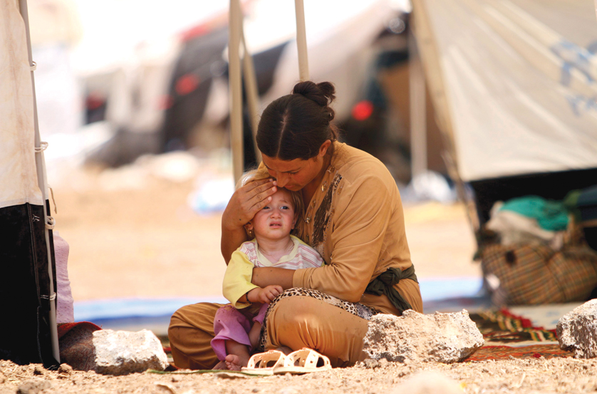 A woman who fled the violence in the Iraqi town of Sinjar sits with a child inside a tent at a camp in Syria's northern town of Qamishli Aug. 17. Returning from a visit to the Kurdish region of Iraq, Syriac Catholic Patriarch Ignace Joseph III Younan called the Islamic State invasion "pure and simple religious cleansing and attempted genocide." (CNS photo/Rodi Said, Reuters) See YOUNAN-CLEANSING Aug. 27, 2014.