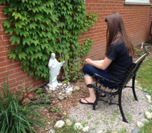 Jackie Beltowski prays before a statue of the Sacred Heart in a prayer garden behind her house.