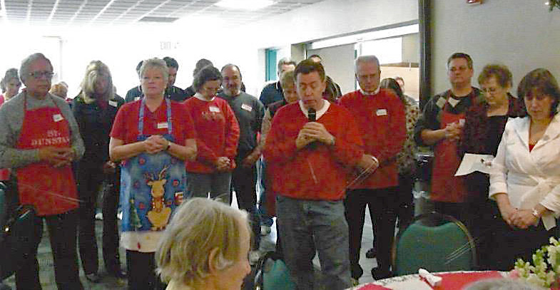 Volunteers bless the food during a Christmas Day dinner at St. Dunstan Church in Garden City in this file photo. Now merged as part of St. Thomas the Apostle Parish, parishioners have continued the tradition. 