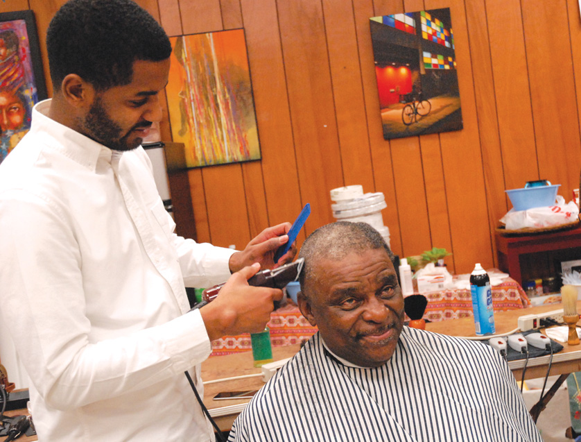 Sebastian Jackson, left, owner of The Social Club Grooming Company in Detroit, cuts the hair of his client, Alonzo, at the Downtown Synagogue on Dec. 15. Volunteers from various faiths, including Catholic and Jewish leaders, participated in the “Grooming on Griswold” event.  