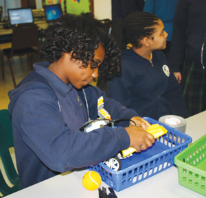 Eighth-grader MaKayla Rawls works diligently on a robot with guidance from UD-Jesuit students Jan. 7.