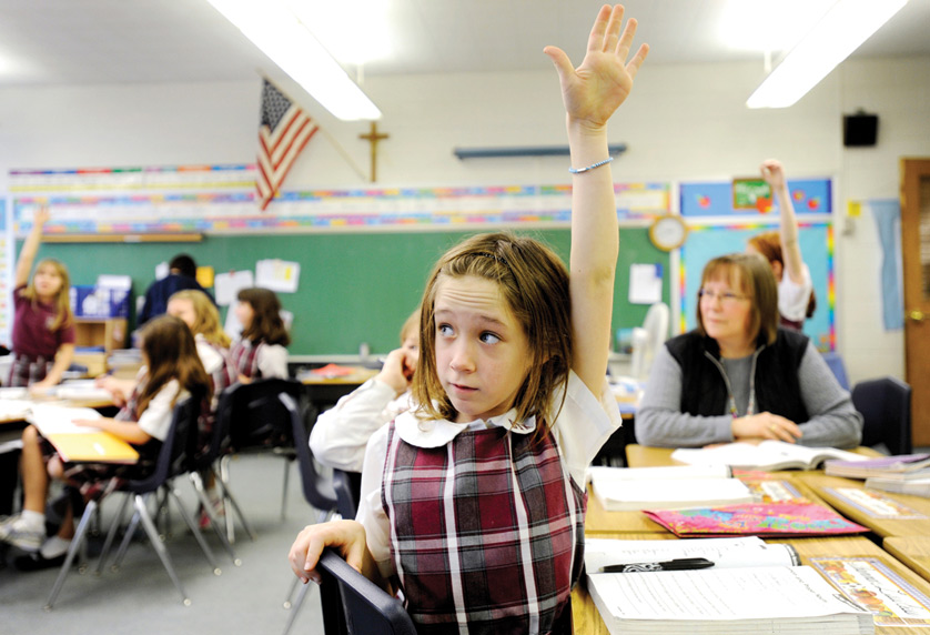 A fourth-grader raises her hand to answer a question at Christ the King School in Irondequoit, N.Y., in this 2011 photo. Even with school out for the summer, the debate is ongoing about the love-them-or-hate-them Common Core State Standards, developed by the National Governors Association and the Council of Chief State School Officers. (CNS photo/Mike Crupi, Catholic Courier) (July 18, 2014) See WASHINGTON LETTER July 18, 2014.        
