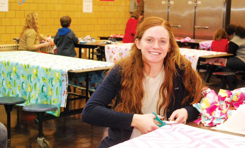 Lilly Blake, a junior at Mercy High School in Farmington Hills and a parishioner of St. Paul on the Lake, Grosse Pointe Farms, cuts fleece at a blanket-making event at Shrine Catholic Grade School, Royal Oak, on Jan. 10. Blake follows the lead of her two older sisters in directing “Blanketed With Love,” a non-profit organization making warm blankets for those in need. Her oldest sister, Sarah, founded the organization in 