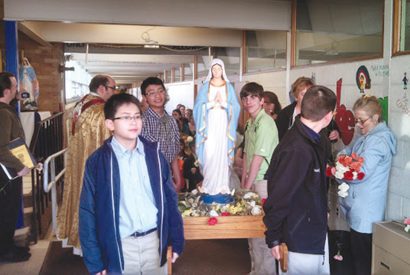 St. Damian School students carry a statue of the Blessed Mother down the halls of the school during a tri-parish May Crowning last year. St. Damian School serves the clustered Westland parish communities of Divine Savior, St. Theodore of Canterbury and St. Damian.