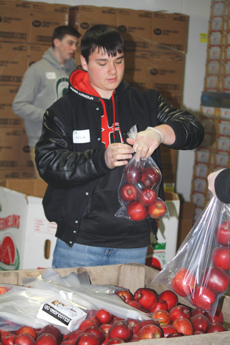 A student bags fruit at Gleaners Food Bank during a “Pledge: Faith in Action” day of service for Dearborn Divine Child High School last year. 