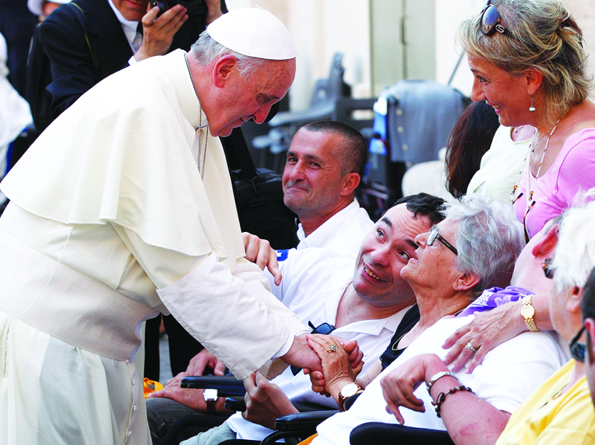 Pope Francis greets people in wheelchairs after celebrating Mass in St. Peter’s Square last summer. 