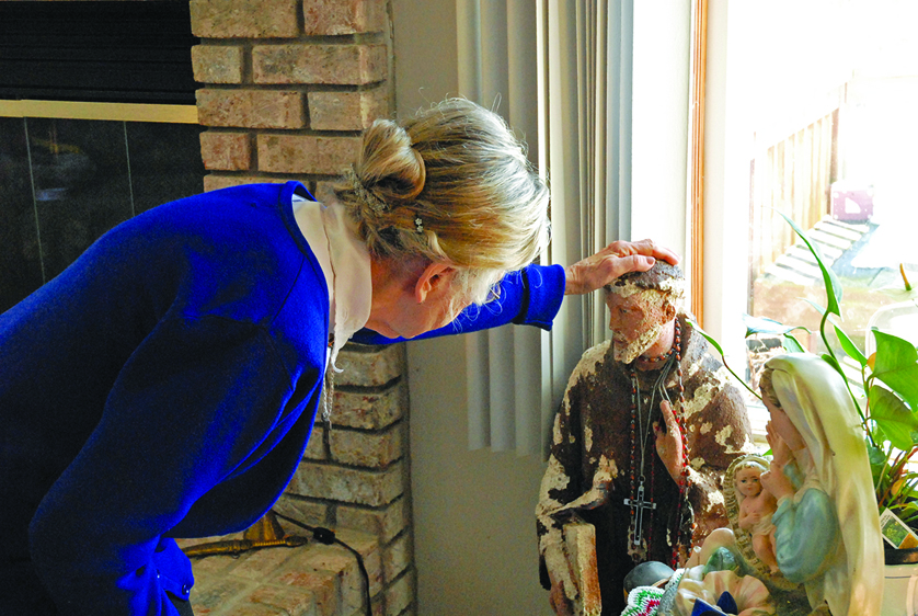 Dorothy “Dolly” Blair gently touches the head of St. Francis — one of the statues she acquired to restore. Blair, a Secular Franciscan, embodies the spirit of St. Francis in other ways as well, including as a poet and owner of three adopted pets.