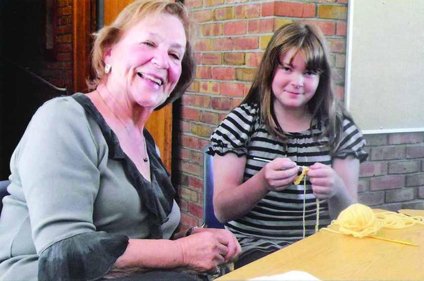 A member of St. Andrew Parish’s needlework ministry works with a young girl learning to crochet. 