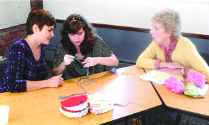 A young woman is shown how to crochet during a recent St. Andrew’s needlework ministry gathering. 