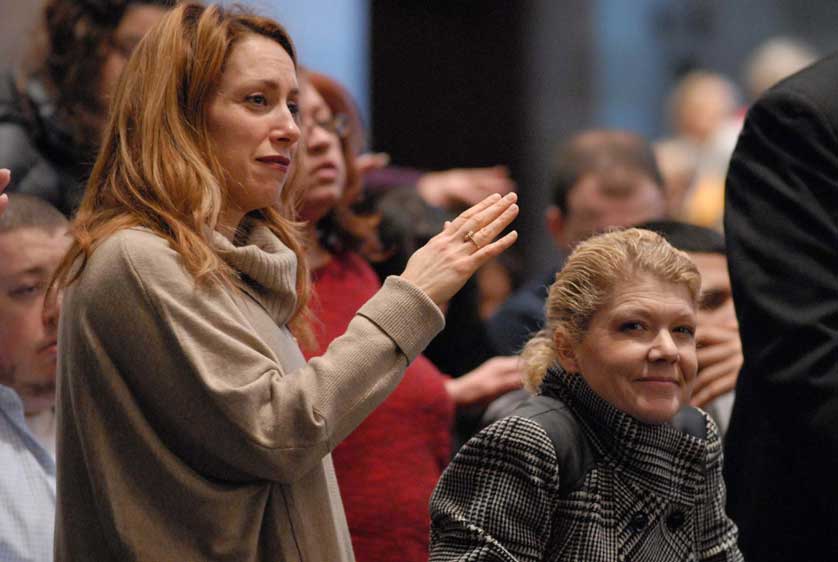 As elect and candidates kneel, sponsors with the rest of the assembly extend their hands in prayer over them during the Rite of Election on Feb. 21 at the Cathedral of the Most Blessed Sacrament.