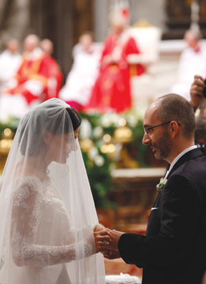 New spouses exchange rings as Pope Francis, pictured in the background, celebrates the marriage rite for 20 couples during a Mass in St. Peter's Basilica at the Vatican Sept. 14. (CNS photo/Paul Haring) 