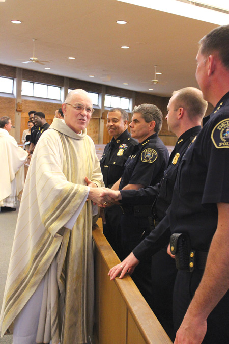 Bishop Donald Hanchon greets police officers at the sign of peace during the Blue Mass on May 16 at St. Christopher Church in Detroit. 