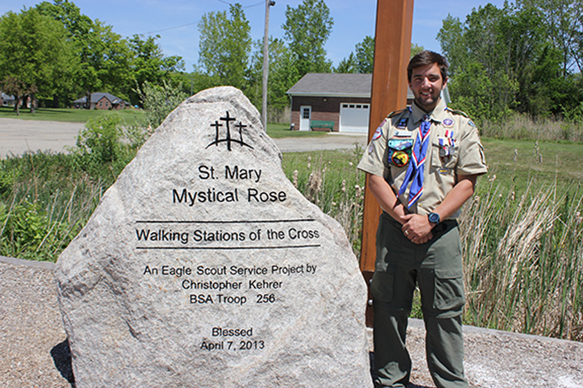 Christopher Kehrer stands by the boulder marking his Stations of the Cross Walking Pathway at St. Mary Mystical Rose Parish in Armada.