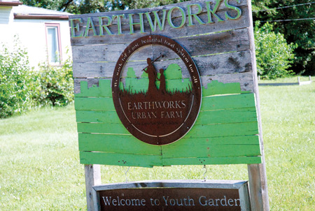 A sign welcoming visitors to the Capuchins' Earthworks Urban Farm in Detroit reads "We work for a just, beautiful food system for all."