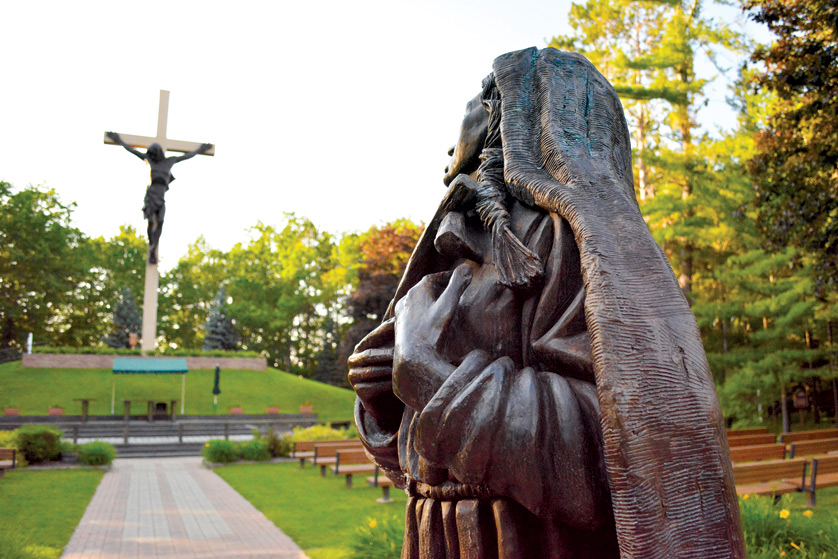 A statue of St. Kateri Tekakwitha gazes at the 55-foot-tall crucifix of the National Shrine of the Cross in the Woods in Indian River, Michigan, the largest crucifix in the world. The recently canonized Native American saint, whose feast day is July 14, is known as a patron of the environment, one of the focuses of Pope Francis' recent encyclical, Laudato Si