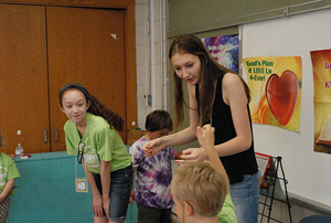 Volunteeers help St. Ambrose campers with science experiments June 26.