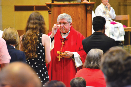Cardinal Thomas Collins of Toronto offers Communion to a conference participant Aug. 10.