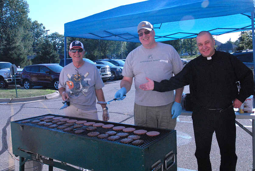 St. Thecla Knights of Columbus members Lou Gatti and Dave Bean grill some food for the parish's guests  alongside associate pastor Fr. Radoslaw Zablocki. The parish, a member of the Macomb County Emergency Rotating Shelter Team (MCREST), was hosting 30 homeless men for the week.