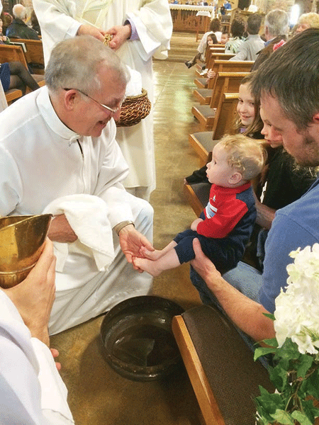 Fr. Mike Verschaeve washes the feet of a baby at St. Joseph the Worker Parish in Lake Orion, where he has been pastor since 2003. Courtesy of St. Joseph Parish