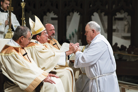 Archbishop Vigneron blesses the hands of Deacon Phillip McCown, who along with his three Detroit classmates is a member of the Knights of Columbus.