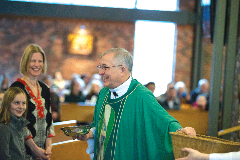 Fr. Mike Verschaeve smiles while receiving the gifts during Mass at St. Joseph the Worker Parish in Lake Orion. 