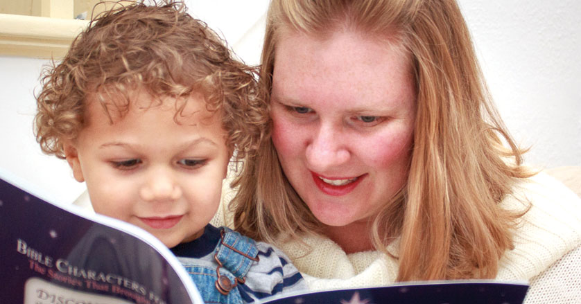 Theresa Pobee-Mensah reads her book, "Bible Characters for Advent," to her son Charlie, at their home in Erie. Family Photo