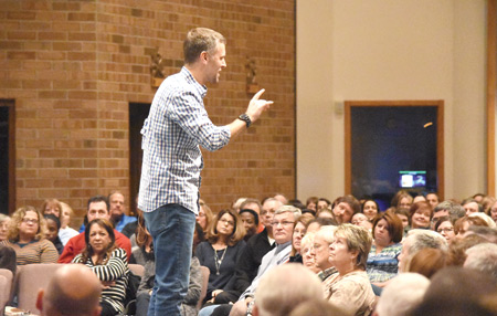 Chris Stefanick, founder of Real Life Catholic, stands on a chair to speak to audience members gathered at St. John Neumann Parish in Canton on Dec. 9 about the "awesome" love of God. Dan Meloy | The Michigan Catholic