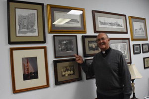 Msgr. John Budde shows photos from St. Mary's history, including its original stone church. Dan Meloy | The Michigan Catholic