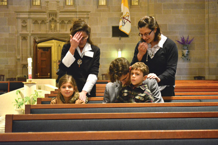 Volunteers from the Dive Mercy Center in Clinton Township pray with families inside the Cathedral after Mass.