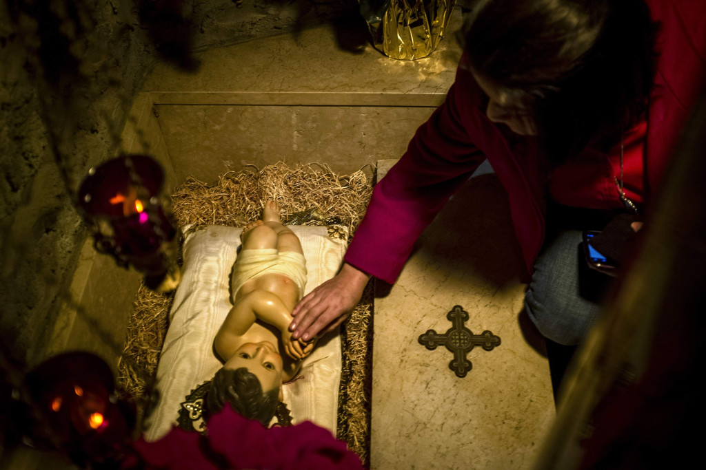 A woman touches a figure of the baby Jesus after Christmas Mass at the Franciscan Monastery in Washington. (CNS photo/James Lawler Duggan, Reuters) 