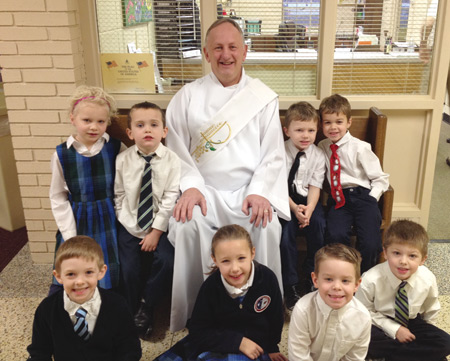 Deacon John Fitzmaurice, principal of St. Mary/McCormick Catholic Academy in Port Huron, sits with students at the school in January. Deacon Fitzmaurice, who was ordained in October 2015, is another example of the growing role of deacons in Church ministries such as education.  Photo by St. Mary/McCormick Academy