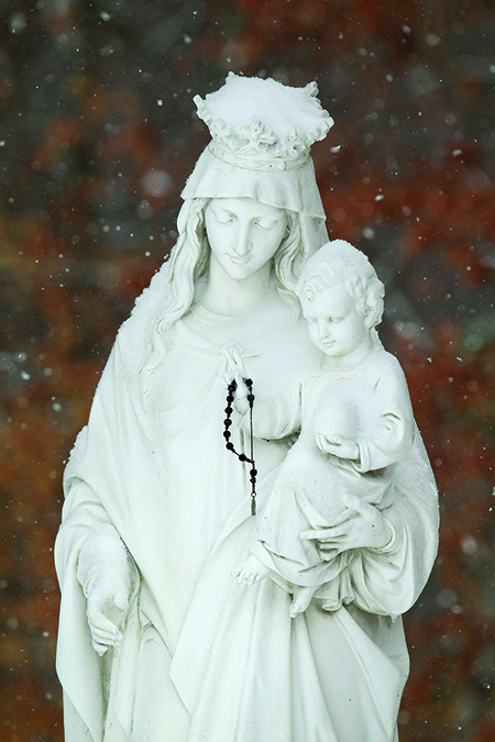 Falling snow makes a backdrop for a statue of Mary and the Christ child outside Jesus the Divine Word Church in Huntingtown, Md., March 3. (CNS photo/Bob Roller) (March 4, 2014)