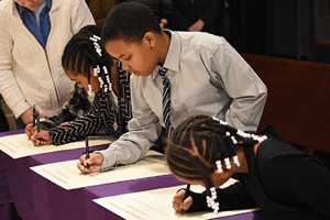 Kyndall and Mya Sims write their names in the Book of the Elect Feb. 13 at the Cathedral of the Most Blessed Sacrament. Dan Meloy | The Michigan Catholic