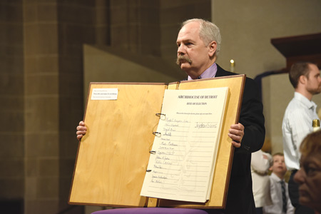 Dan McAfee, director of Christian worship for the Archdiocese of Detroit, holds open the Book of the Elect.