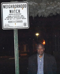 Fr. Michael Nkachukwu, pastor of Detroit's Our Lady Queen of Heaven/Good Shepherd Parish, walks by a neighborhood watch sign in the parish's Osborn neighborhood