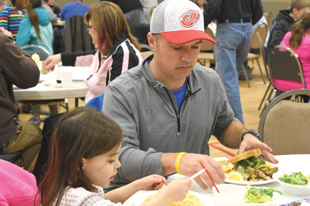 Mitch Koleczko and his daughter, Sofia, sample the food at St. Germaine School's Lenten fish fry Feb. 26 in St. Clair Shores. Kaleczko has sampled 11 different fish fries in the Archdiocese of Detroit and reviews them on his Facebook page, "Mitch's Friday Fish Fry Review". Photos by Dan Meloy | The Michigan Catholic
