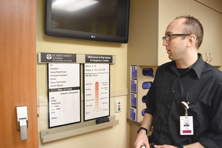 Dustin Deriemacker, RN, shows some of the large-print charts to help hospital workers better care for senior patients.